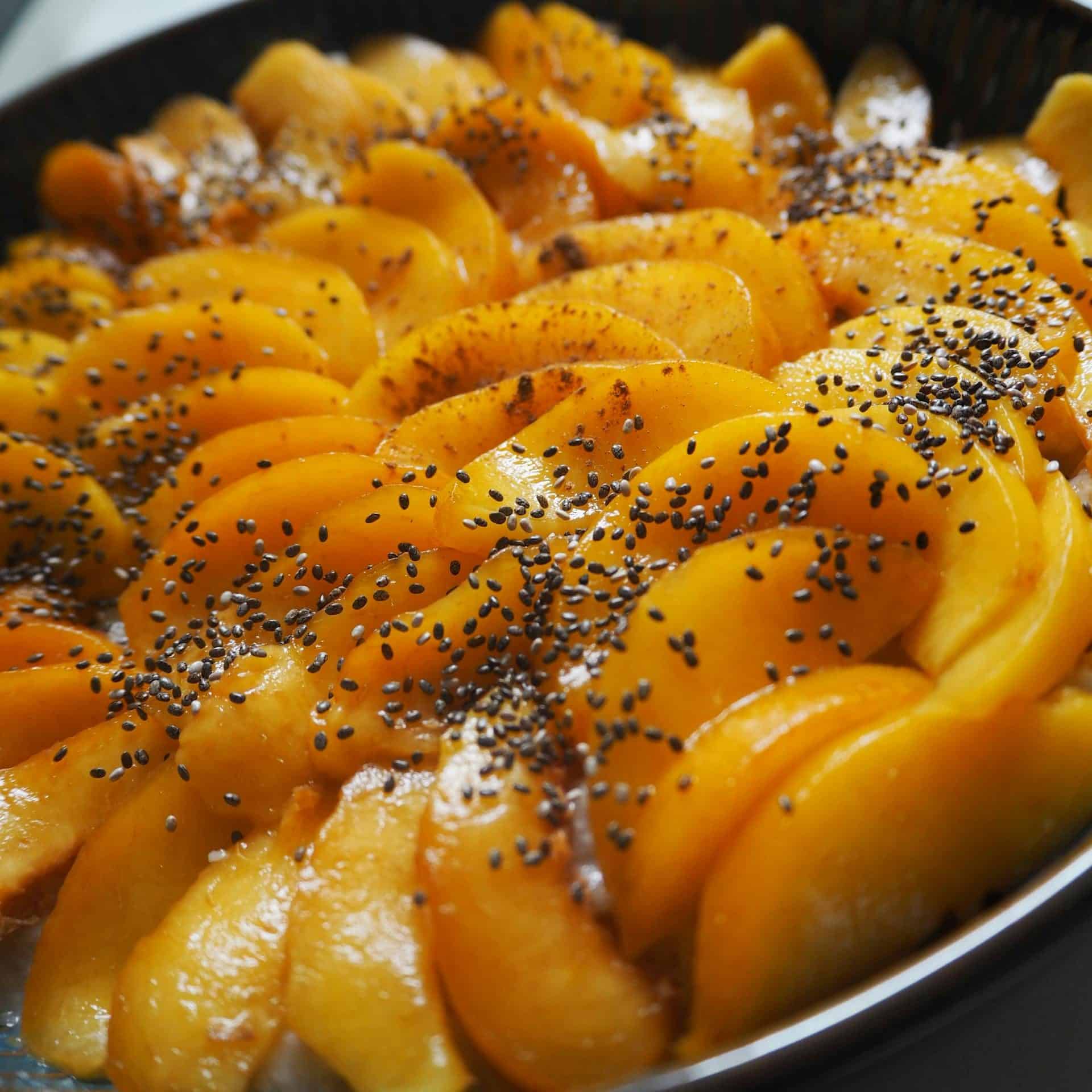 Close-up of a homemade peach dessert topped with seeds, perfect for summer treats.