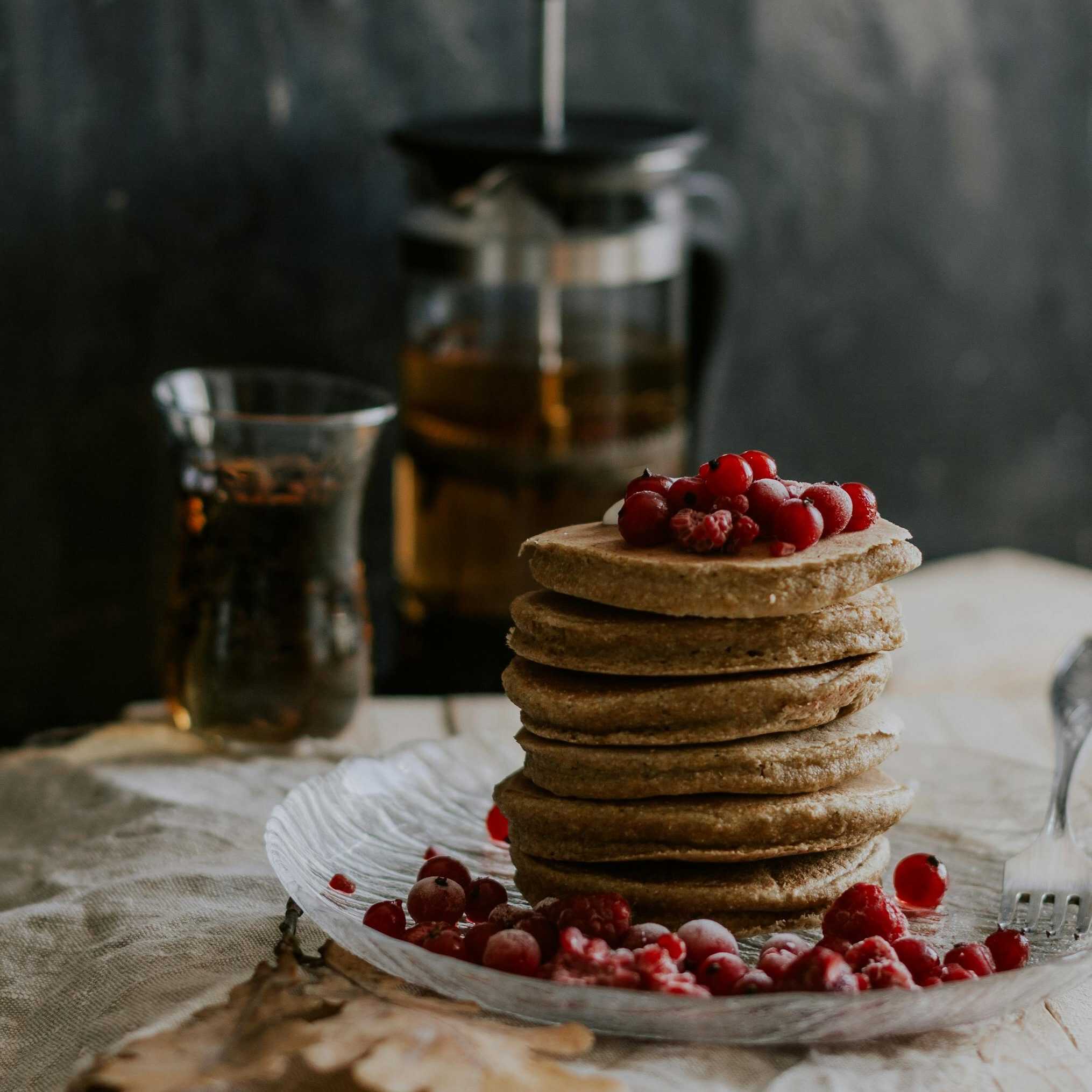 Indulge in a rustic breakfast with homemade pancakes topped with fresh berries and coffee.