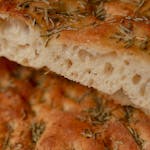 Fresh, golden focaccia bread topped with herbs, perfect for culinary projects.