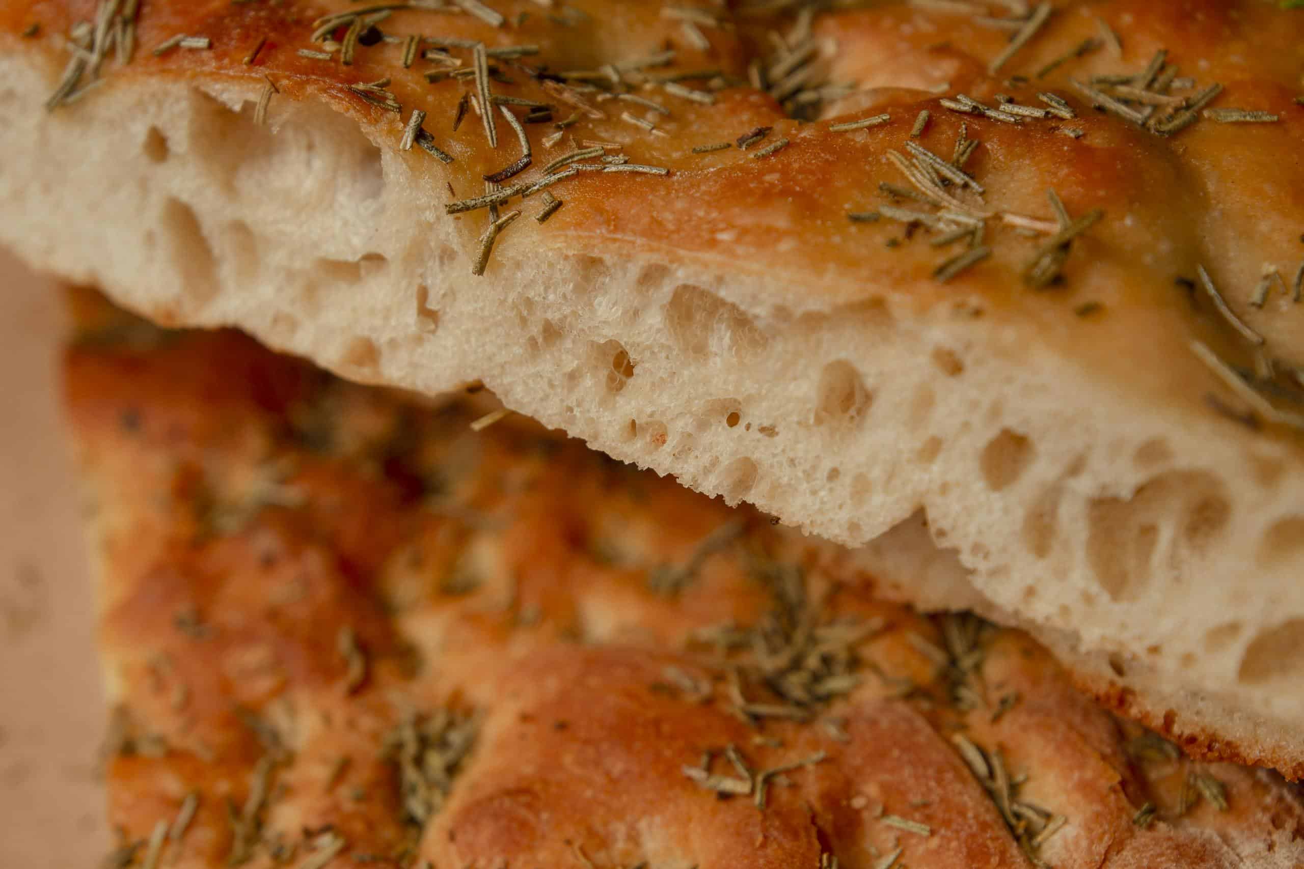 Fresh, golden focaccia bread topped with herbs, perfect for culinary projects.