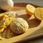 Fresh lemon cookies on a tray near a snowy mountain view and dried plants.