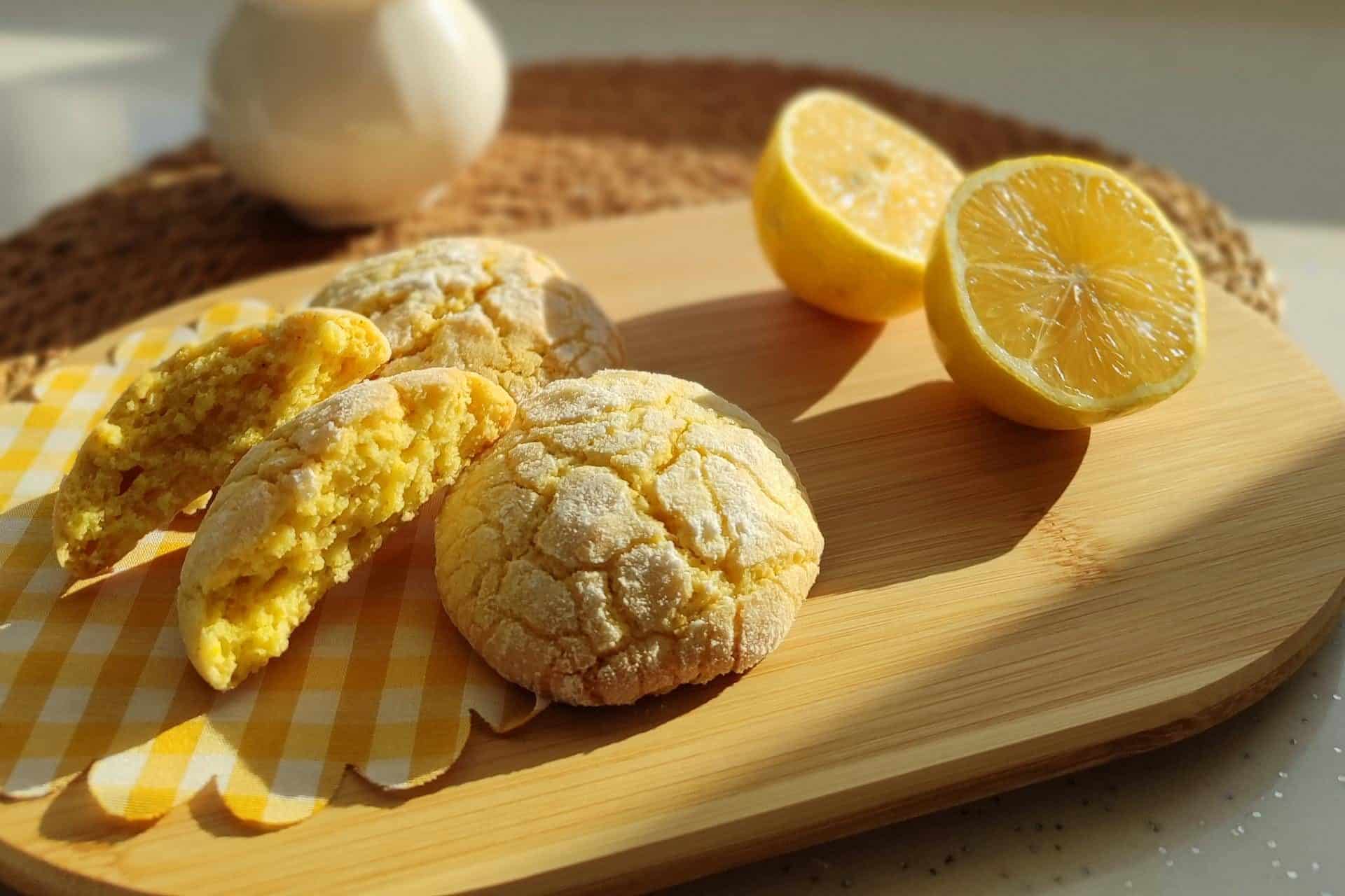 Fresh lemon cookies on a tray near a snowy mountain view and dried plants.