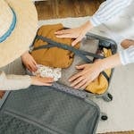 A woman and child pack clothes in a suitcase, preparing for a vacation.