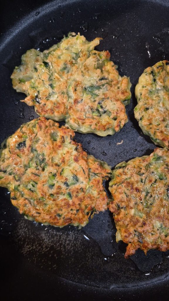 crispy zucchini fritters frying in a pan