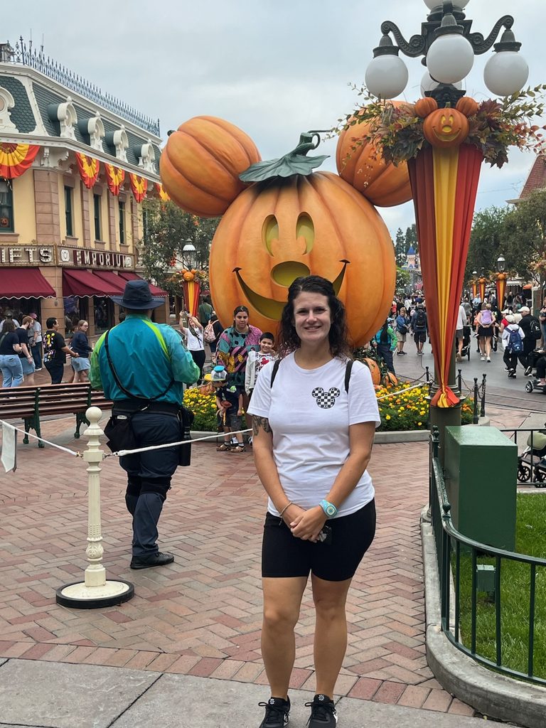 woman wearing a disney top with biker shorts, walking shoes, and a MagicBand